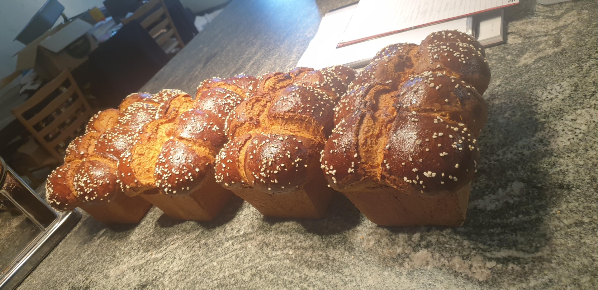 Four plaited brioche loaves with pearl sugar cooling on granite