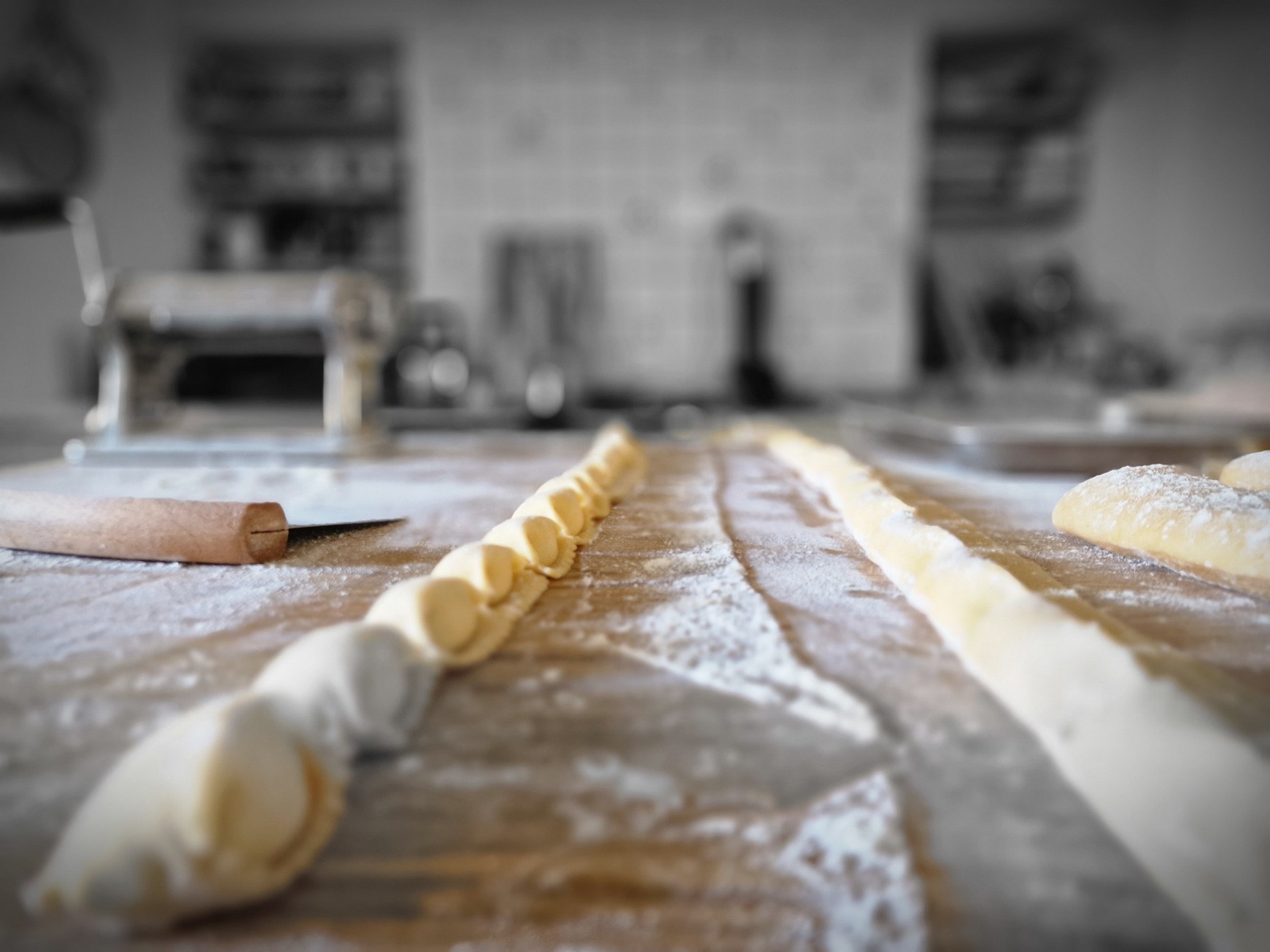 Fresh pasta dough on a floured wooden surface beside a pasta machine